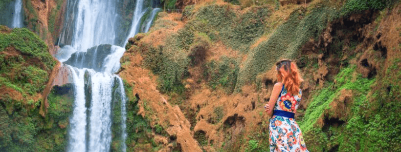 Person standing at the base of a waterfall