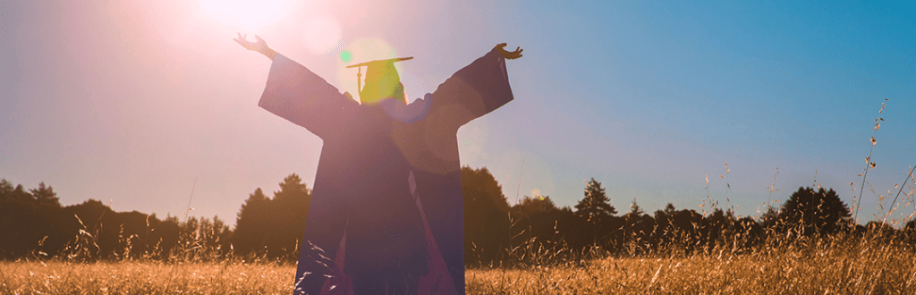 Student walking in a field after graduation.